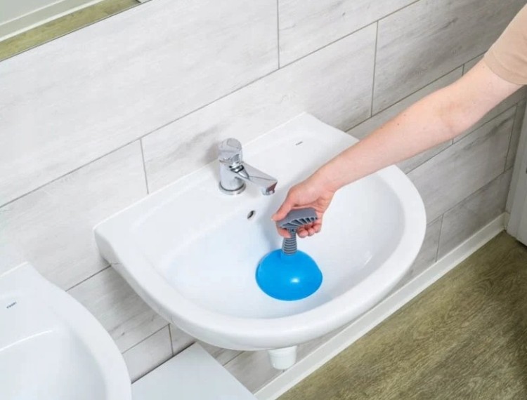 Przepychacz sanitarny fi 12 cm z gumową końcówką i ergonomiczną rączką trzymany nad umywalką