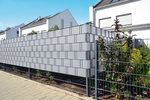 Jasnoszara taśma ogrodzeniowa Cellfast 35m x 19cm zamocowana na metalowym panelu ogrodzeniowym