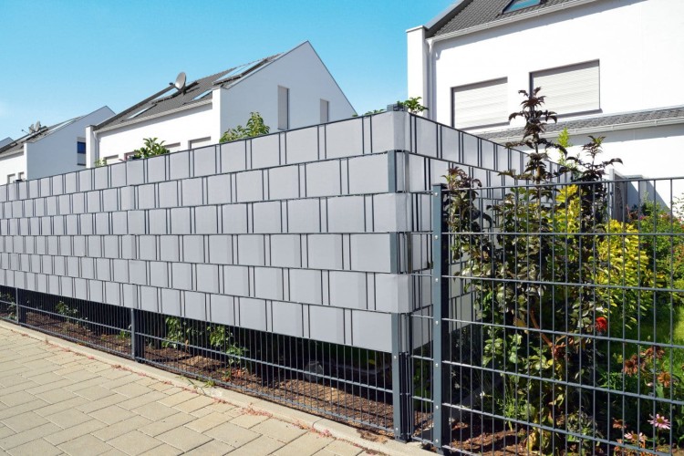 Jasnoszara taśma ogrodzeniowa Cellfast 35m x 19cm zamocowana na metalowym panelu ogrodzeniowym