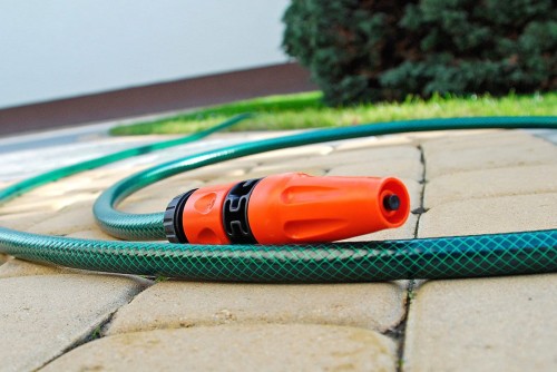 Pomarańczowy zraszacz na zielonym wężu